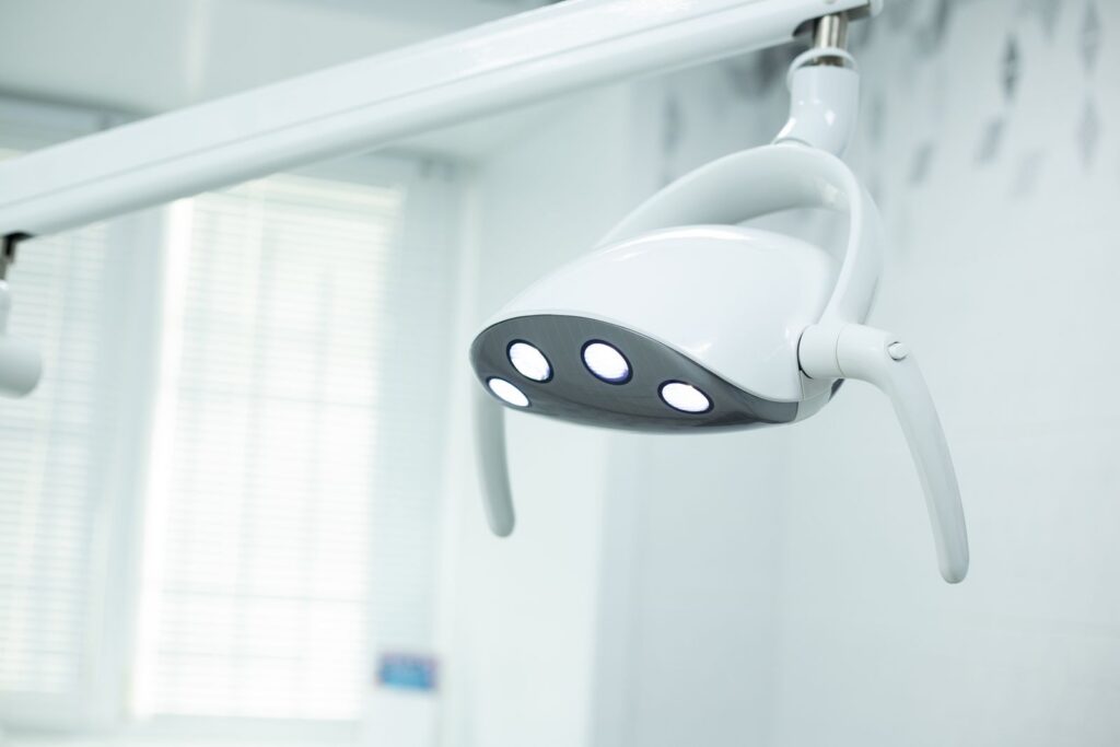 A modern dental examination light above an empty treatment chair.