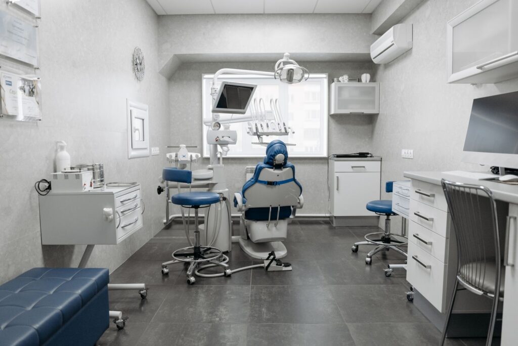 A spacious dental treatment room with white walls and modern equipment.