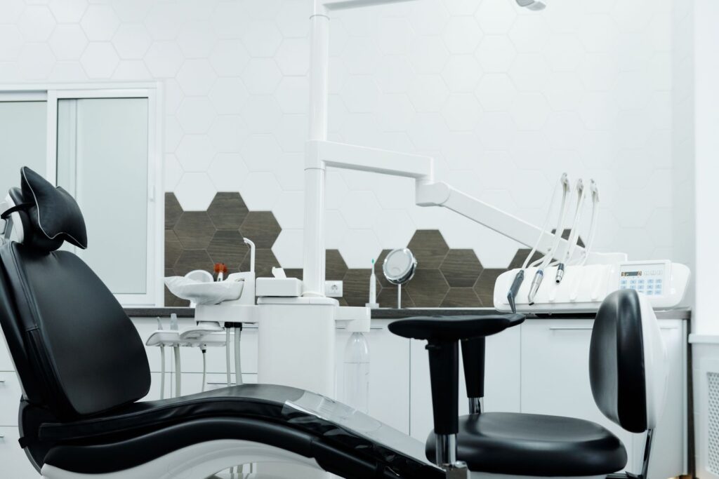 A dental chair and equipment seen from the side in an empty treatment room.