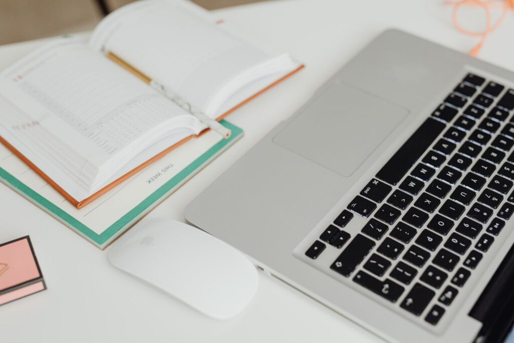 A laptop and an open paper calendar side by side on a desk.